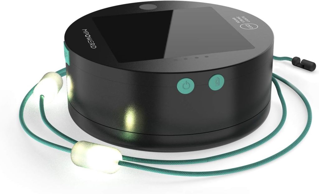A round, black electronic device with a digital screen, power buttons, and a teal cord featuring two white, glowing earbuds attached—MOMMED branded and perfect for fans of the best solar gadgets for off-grid camping 2025.